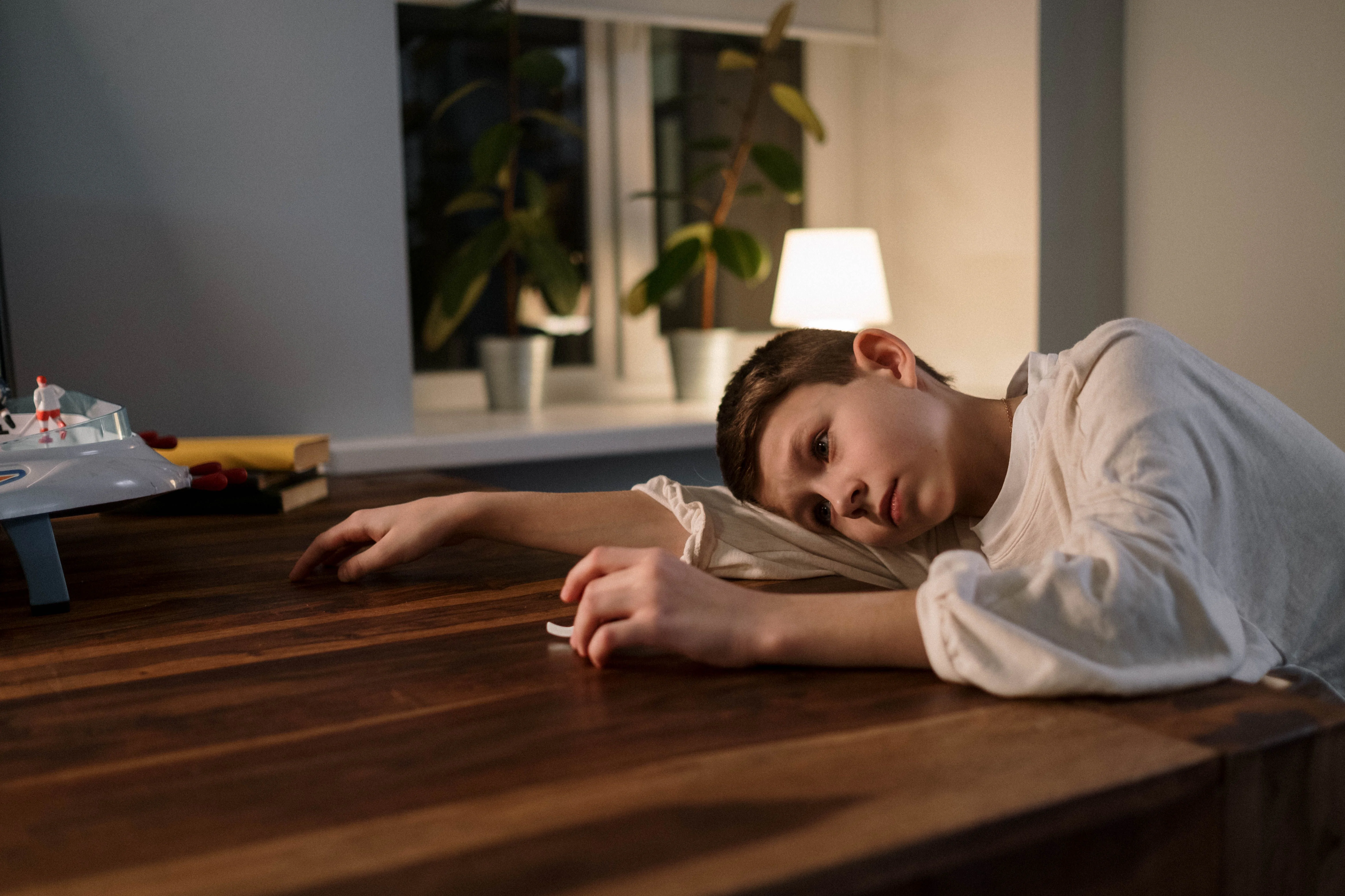 A withdrawn child lying on a table, staring into the distance — the childhood wounds behind compulsive sexual behavior