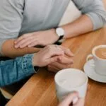 Couple sharing a coffee holding hands, trust and accountability